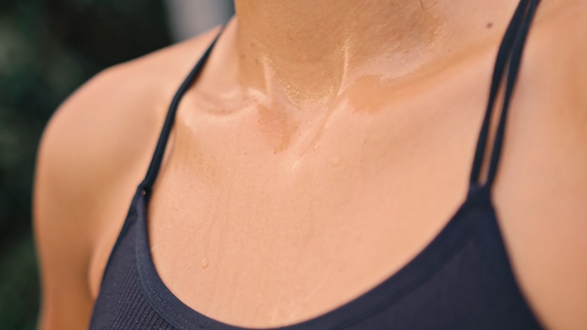 A close-up of a woman's sweaty chest in a black tank top after exercising